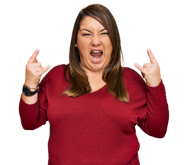 Beautiful brunette plus size woman wearing casual clothes shouting with crazy expression doing rock symbol with hands up. music star. heavy concept.