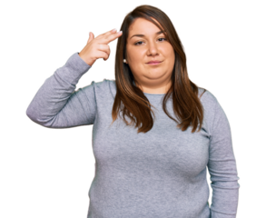 Beautiful brunette plus size woman wearing casual clothes shooting and killing oneself pointing hand and fingers to head like gun, suicide gesture.