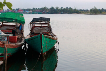 Moored traditional khmer fishing boats on calm water, creating a serene atmosphere in Kampot Cambodia