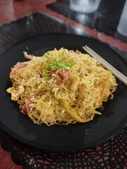 Close up to a plate of pancit bihon or Filipino stir-fried rice noodles, authentic local traditional dish from Philippines