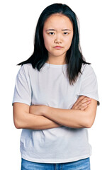 Fototapeta premium Young chinese woman wearing casual white t shirt skeptic and nervous, disapproving expression on face with crossed arms. negative person.