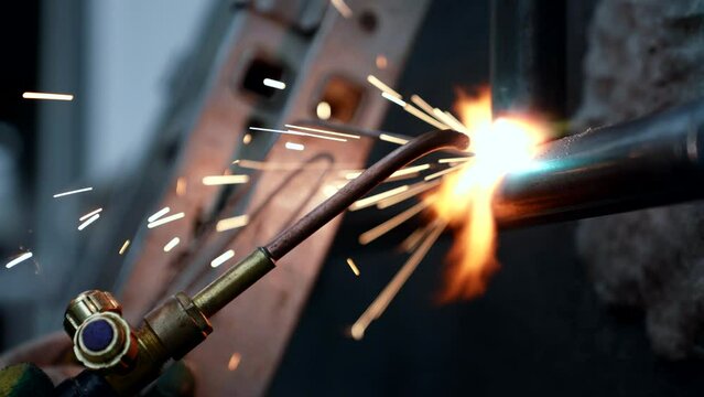 worker using welding machine for welding metal pipes in plant, closeup view, professional welder
