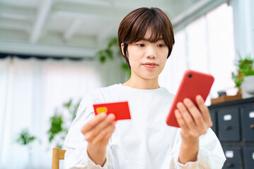 カードを持ってスマートフォンを操作する女性
