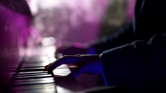 man playing piano in darkness, musician playing jazz melody in nightclub, closeup view of hands