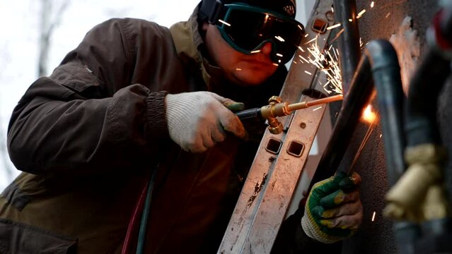welding process in construction site, welder installing metal pipes on facade of house, repair works