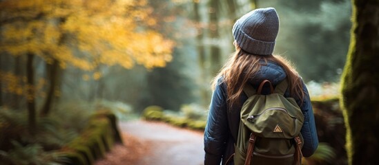 Woman tourist in woodland on misty autumn morning, wearing knit hat and backpack.
