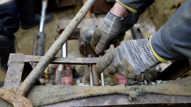 handymen working in construction site, workers installing water or gas pipes in trench, details view