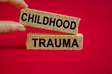 Childhood trauma symbol. Concept words Childhood trauma on brick blocks. Beautiful red background....