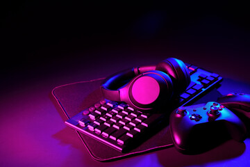 Headphones, joystick and computer keyboard on black table