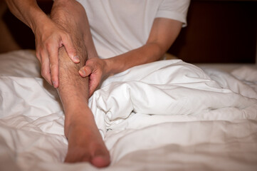 Fototapeta na wymiar close up of man hand touching and massage calf on bed, leg cramp muscle pain