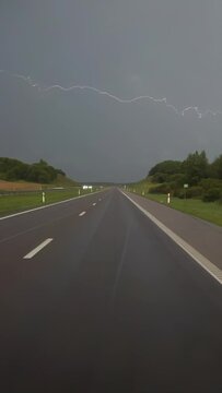 Driving on a highway in a thunderstorm and lightning, vertical slow motion