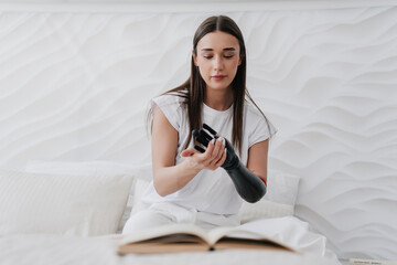 Focused girl adjusting cyber artificial arm at home. Electronic hi technologies for medicine needs....