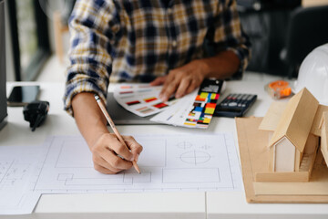 business man hand working and laptop with on on architectural project at construction site at desk