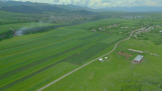 Aerial view of the grand canyon with steep rocky walls, overgrown with green grass and trees, in summer in cloudy weather. Along the banks are villages, fields. Dzoraget Canyon, Lori fortress. Armenia