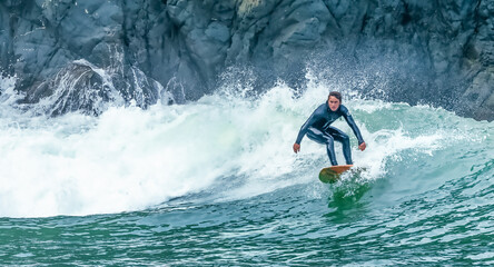 San Francisco, California, USA - October 23, 2021, A surfer rides a wave with cliffs in the...