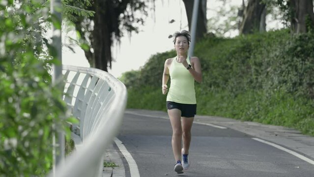 young asian woman female athlete jogging running training outdoors on the road in park