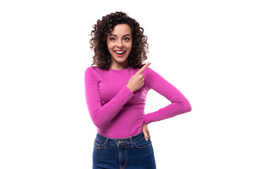 pretty smiling young curly brunette woman dressed in a purple turtleneck points with her hands at the advertisement