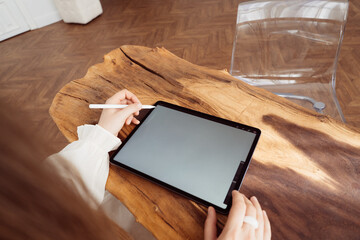 Girl holding a tablet on the background of a wooden table
