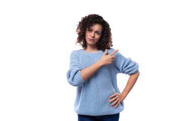 doubtful young curly brunette woman dressed in a blue sweater look suspiciously at the camera