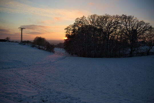 Stimmungsvoller Sonnenuntergang am kalten Winterabend nach dem ersten Schnee