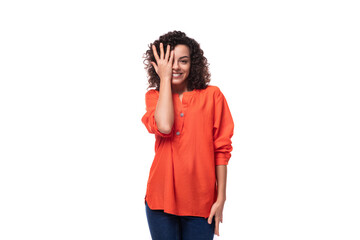 young curly brunette woman dressed in an orange blouse on a white background