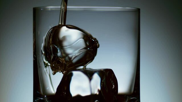 Stream of Liquor Pouring into Glass with Ice