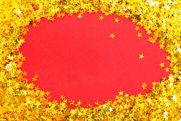 Naklejka na ściany i meble christmas shiny red background with festive golden confetti like a frame with copy space for text.
