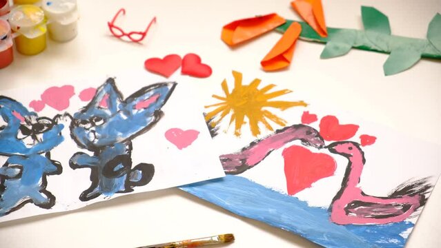 Child painting  couple swan, hearts, making crafts from paper. Handmade concept for birthday, mothers day or Valentines day. Education. Inspiration and imagination