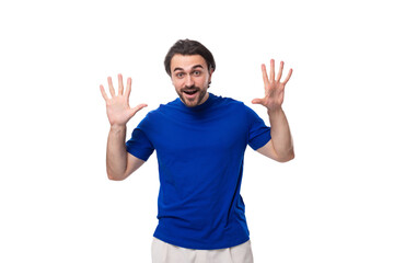 young surprised handsome european man with black hair and beard dressed in a blue t-shirt on a white background with copy space