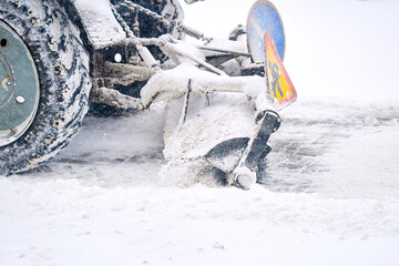 Tractor with rotating brush sweeps snow from snowy sidewalk during snowfall. Snow removal work,...