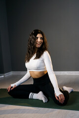 Fototapeta na wymiar Pretty woman in white sportswear doing morning exercises on the mat and doing yoga