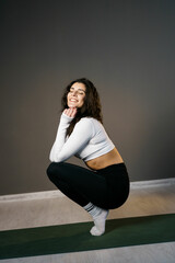 Pretty woman in white sportswear doing morning exercises on the mat and doing yoga