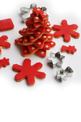 Christmas tree made of star shaped shortcrust cookies with red sugar glaze and cookies and cookie cutters on white background