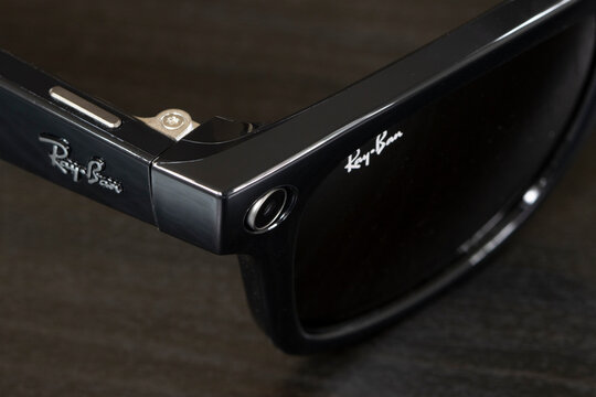 Portland, OR, USA - Dec 5, 2023: Closeup of the built-in ultra-wide 12 MP camera and its control button on a pair of new Ray-Ban Meta Wayfarer smart glasses isolated on a dark gray background.