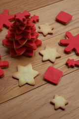 Christmas tree made of star shaped shortcrust cookies with red sugar glaze and other cookies on wooden table. Christmas background