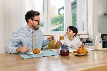 Working dad is having breakfast with his son.
