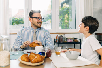 Yong boy and his father having breakfast together.