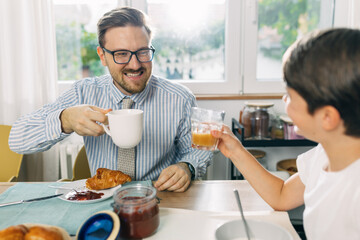 Happy father enjoy having breakfast with his son.