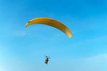Paragliding in the sky over the sea. The concept of parachute flight. Tandem skydiver pilot and passenger fly on a sunny day.