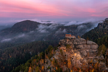Jetrichovice, Czech Republic - Aerial view of Mariina Vyhlidka (Mary's view) lookout with foggy Czech autumn landscape and colorful pink sunrise sky in Bohemian Switzerland National Park