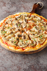 Pizza with fresh portobello mushrooms, mozzarella, garlic, tomatoes and parsley close-up on a wooden board on the table. Vertical