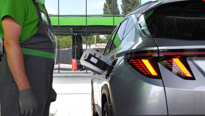 Fuel Station Assistant Near A Vehicle With Opened Fuel Tank Hatch Is Preparing To Refuel