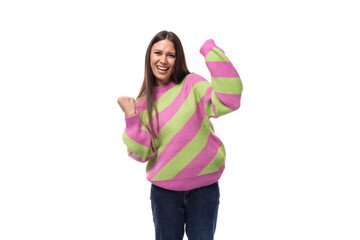 pretty positive cheerful young european brunette woman dressed in a striped pink-green pullover on a white background with copy space