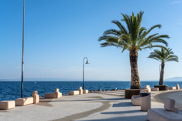 palm trees on beachfront promenade at porto Santo Stefano village on Mediterranean shore, Italy - obrazy, fototapety, plakaty