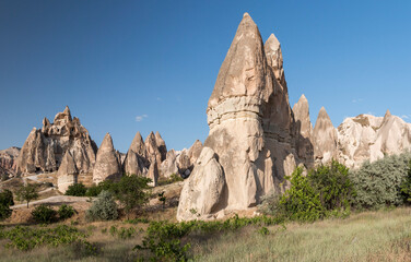 Fototapeta na wymiar Fairy Chimney and a carved churched in the background in Rose Valley in Cappadocia, Turkey