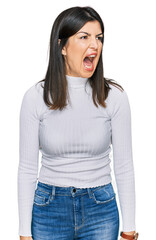 Fototapeta premium Beautiful brunette woman wearing casual clothes angry and mad screaming frustrated and furious, shouting with anger. rage and aggressive concept.