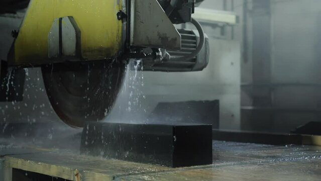 Cutting porcelain stoneware material with a special saw for the manufacture of tiles for finishing facades and tombstones. Production for the production of ceramic plates with digitization. Slow