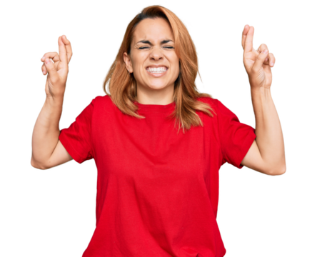 Hispanic young woman wearing casual red t shirt gesturing finger crossed smiling with hope and eyes closed. luck and superstitious concept.