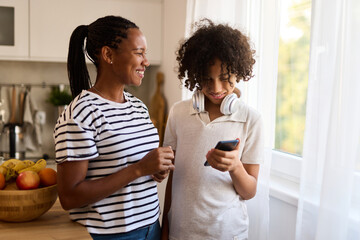 Teenage boy and his mother using smart phone at home