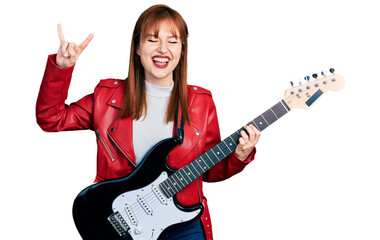 Redhead young woman playing electric guitar doing rock gesture smiling and laughing hard out loud...